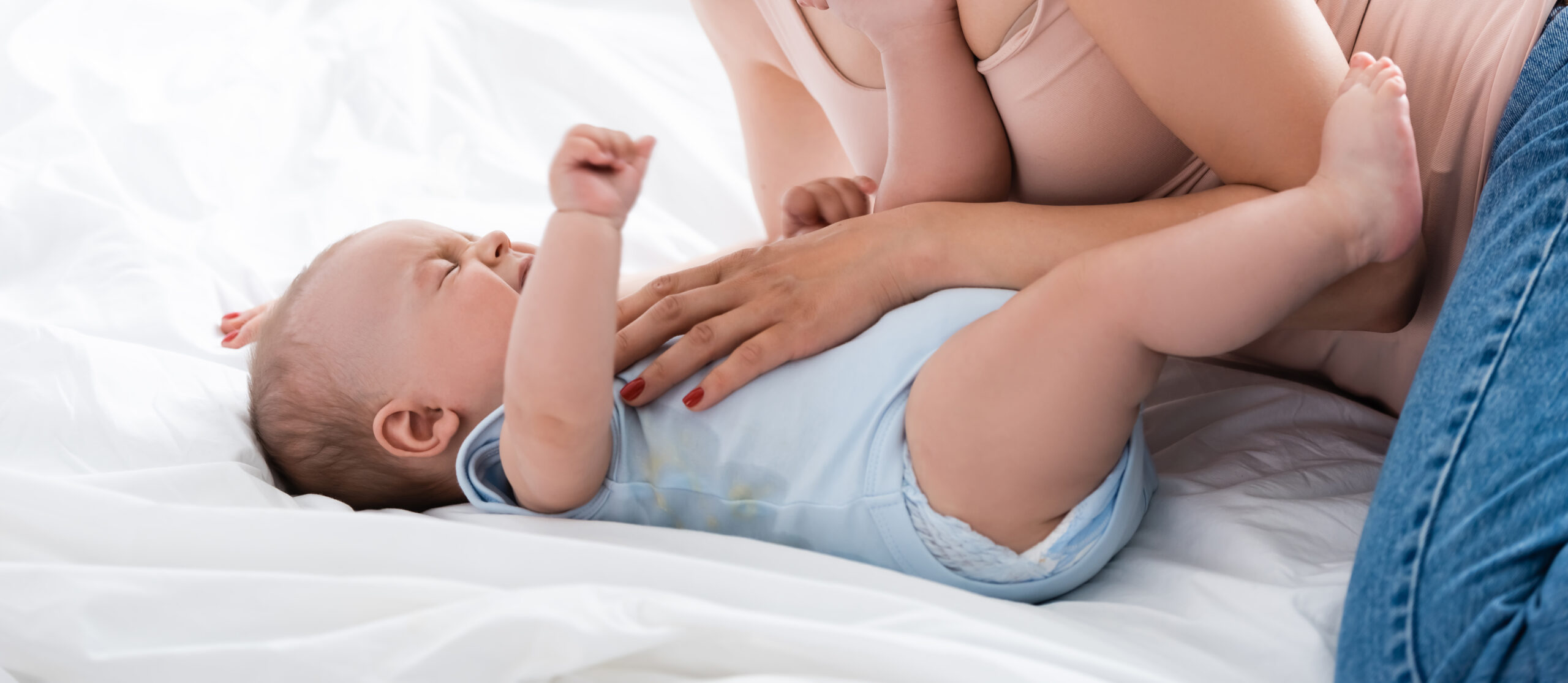 attractive mother looking at crying baby boy in bedroom