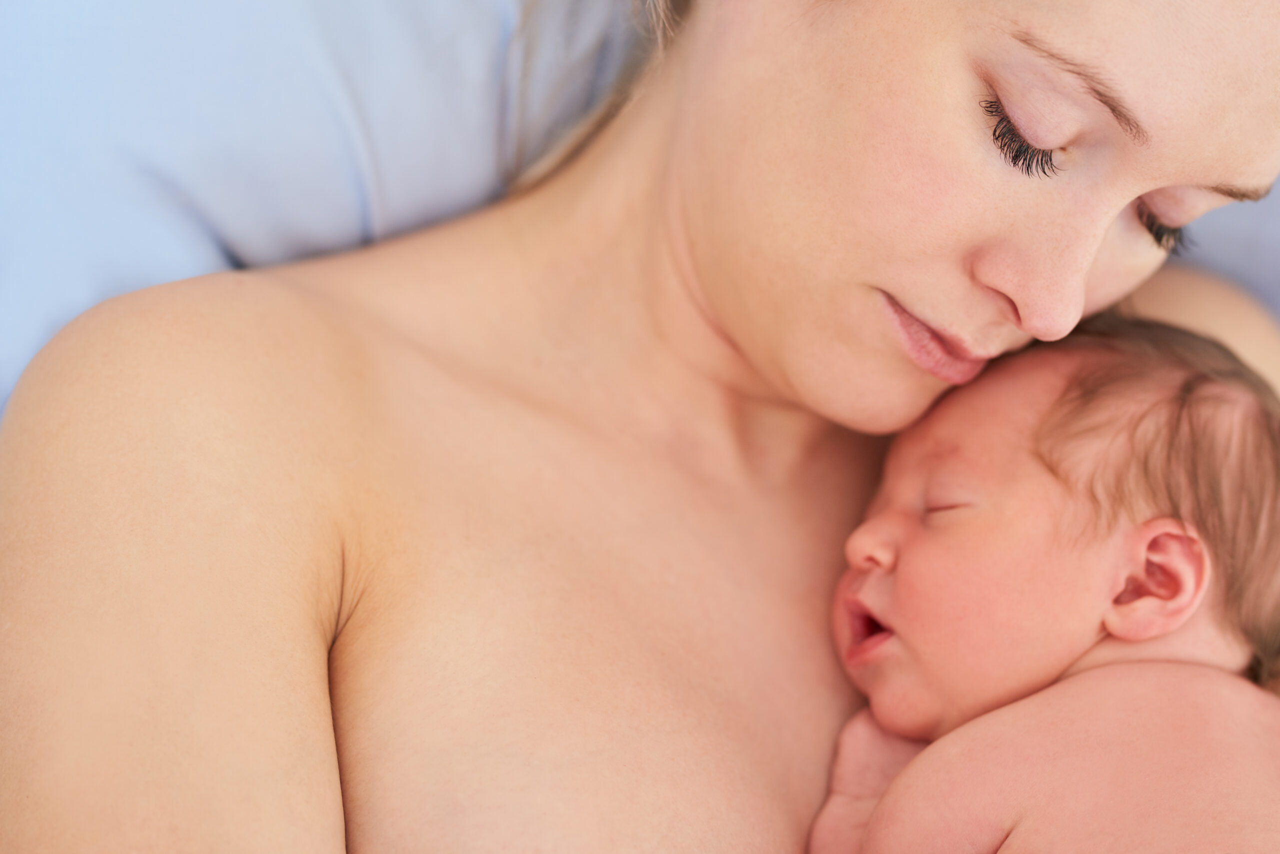 Shot of a beautiful young mother and her newly born baby girl sleeping in a hospital bed together.