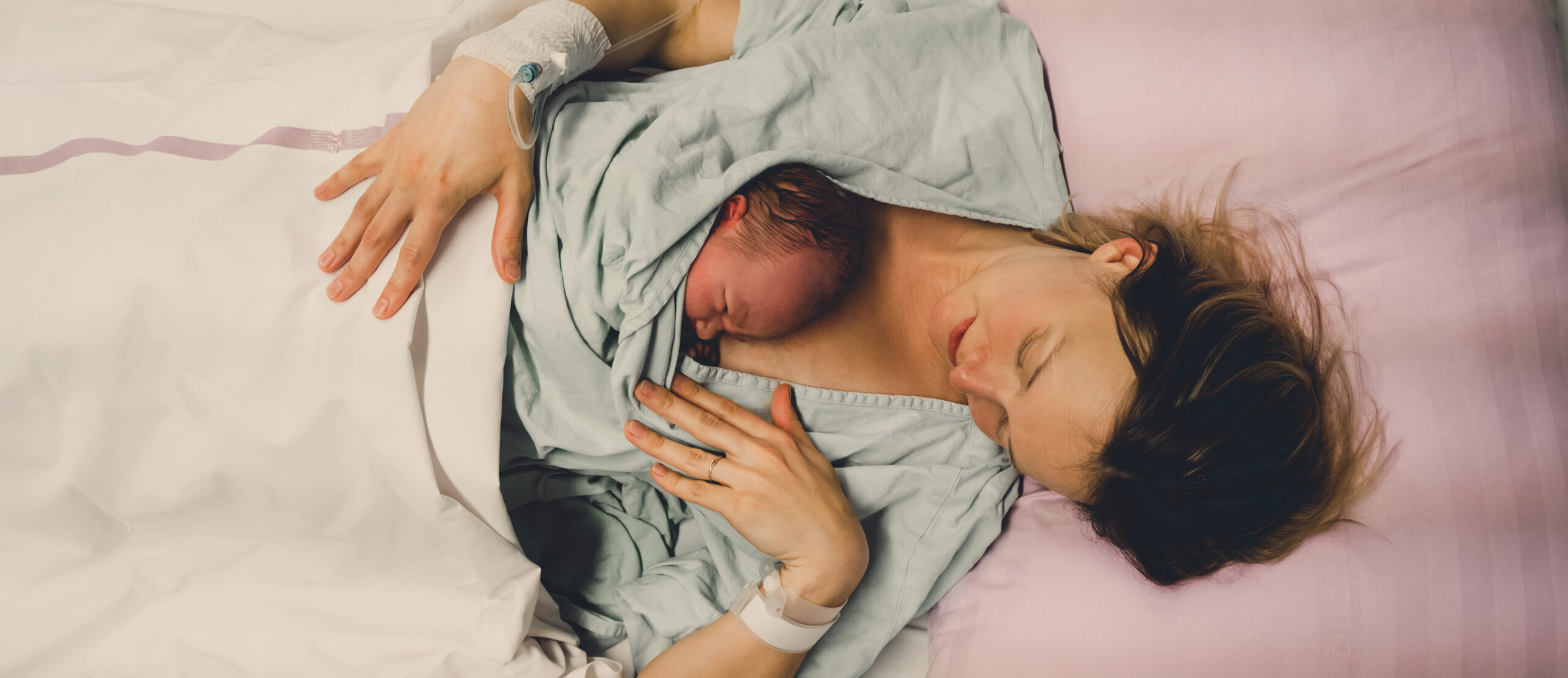 Mother and newborn. Child birth in maternity hospital. Young mom hugging her newborn baby after delivery. Woman giving birth. First moments of baby life after labor.