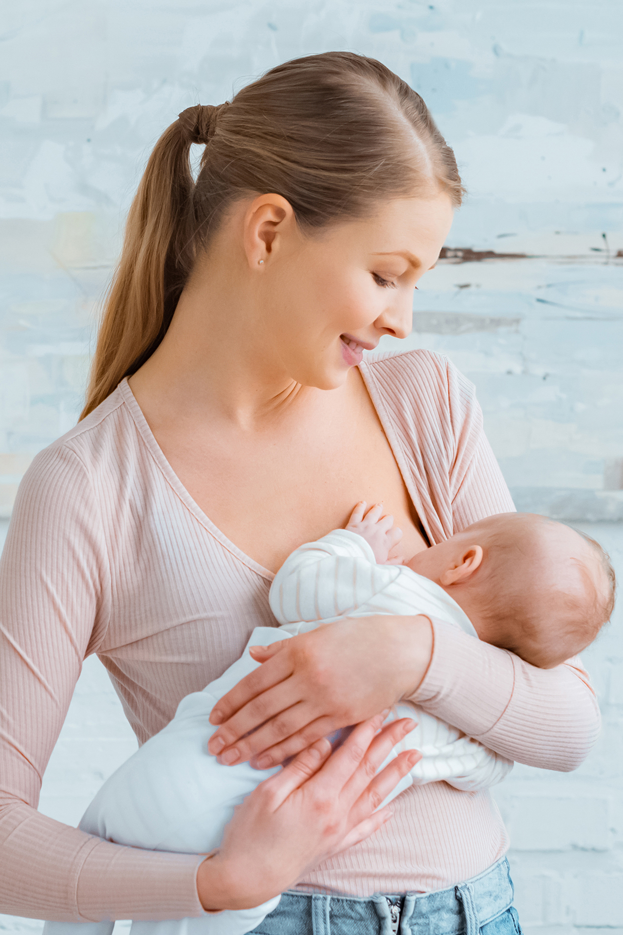 beautiful smiling young mother breastfeeding baby at home